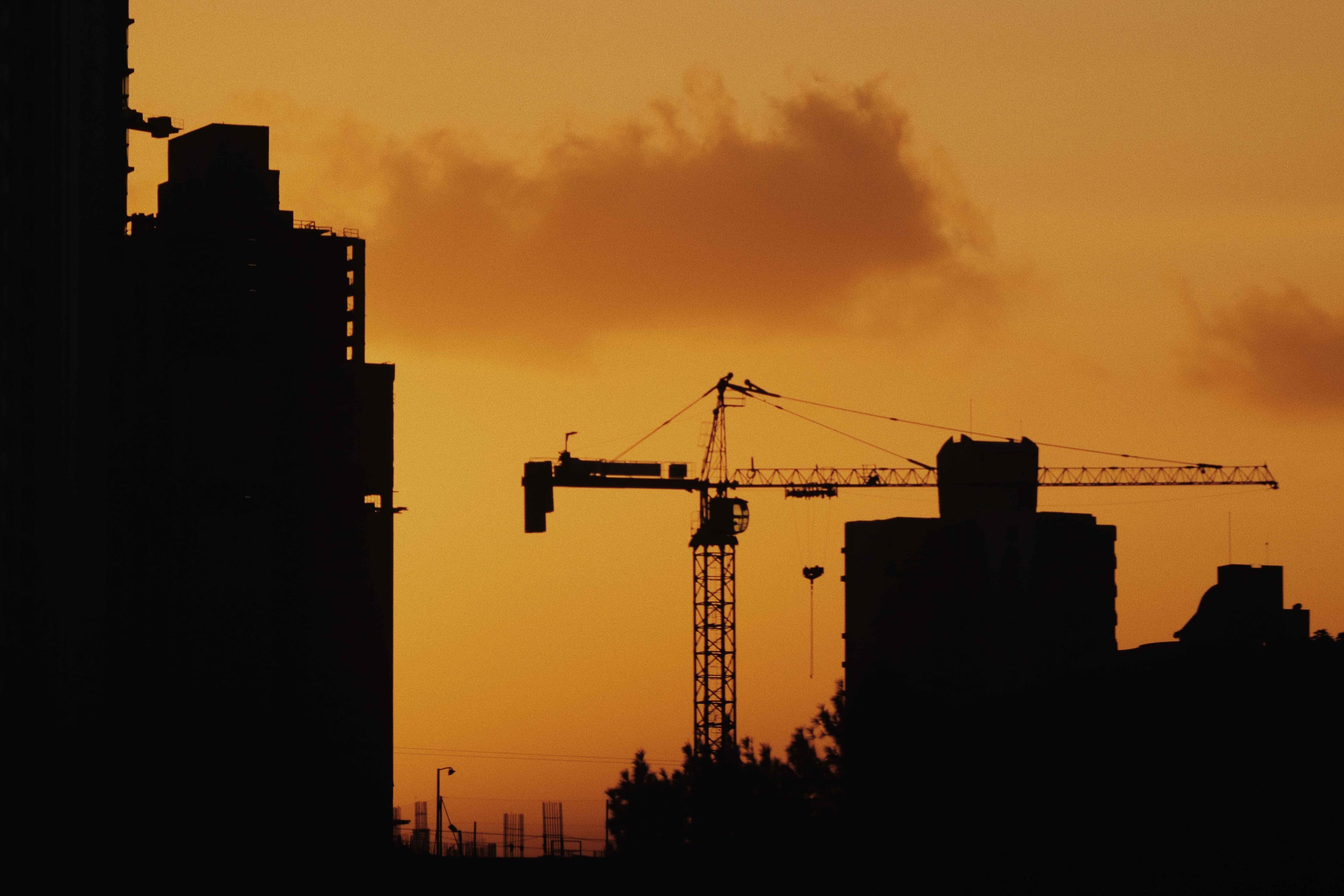 Construction site at sunset with cranes and steelwork