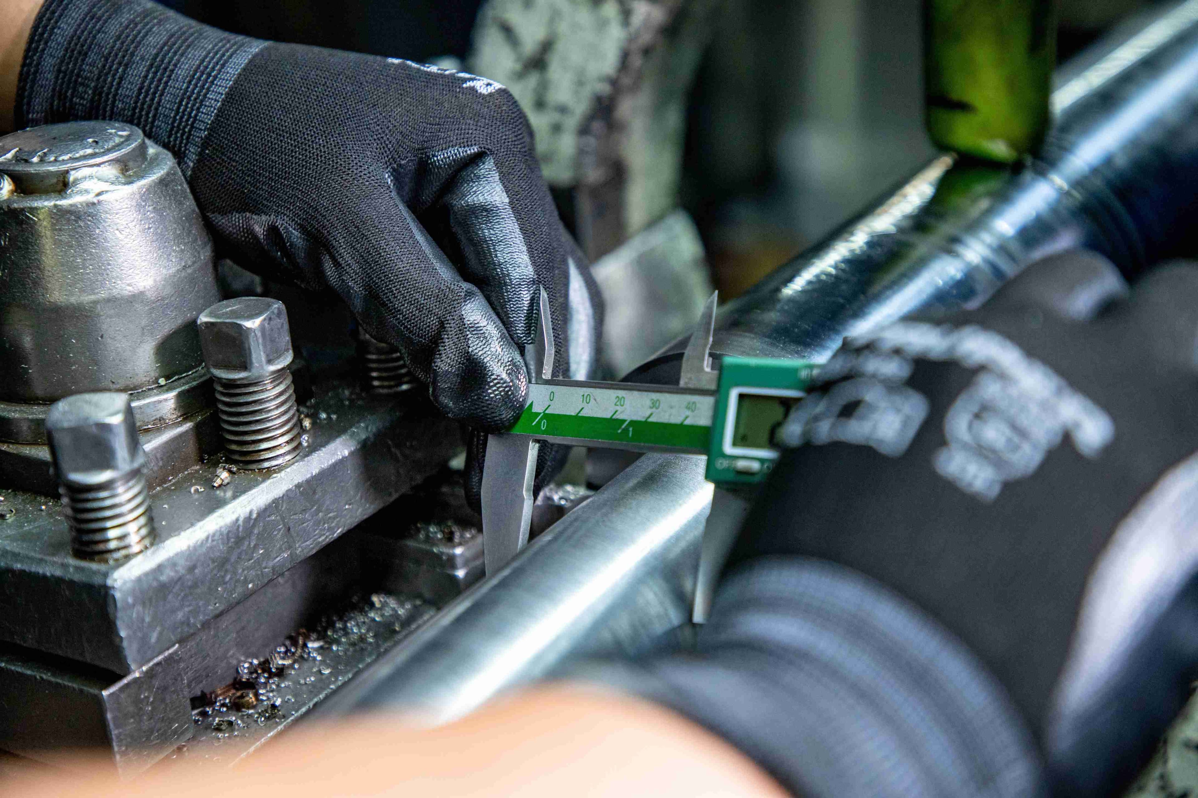 Technician measuring a steel component with a digital caliper